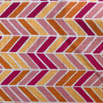 Detail of fabric in a geometric herringbone print in pink, orange and yellow on a white field.