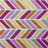 Detail of fabric in a geometric herringbone print in pink, orange and yellow on a white field.