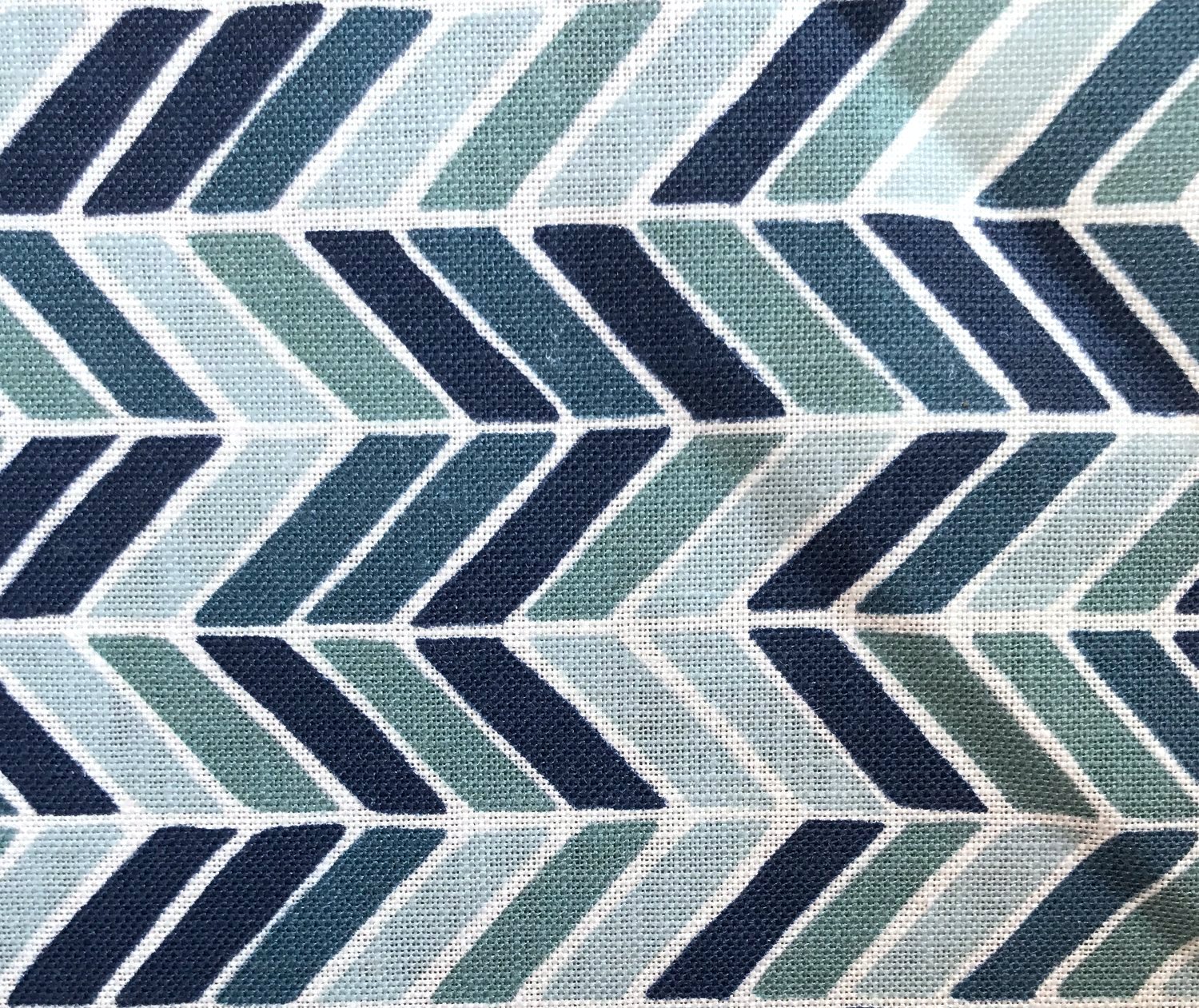 Detail of fabric in a geometric herringbone print in blue, turquoise and navy on a white field.