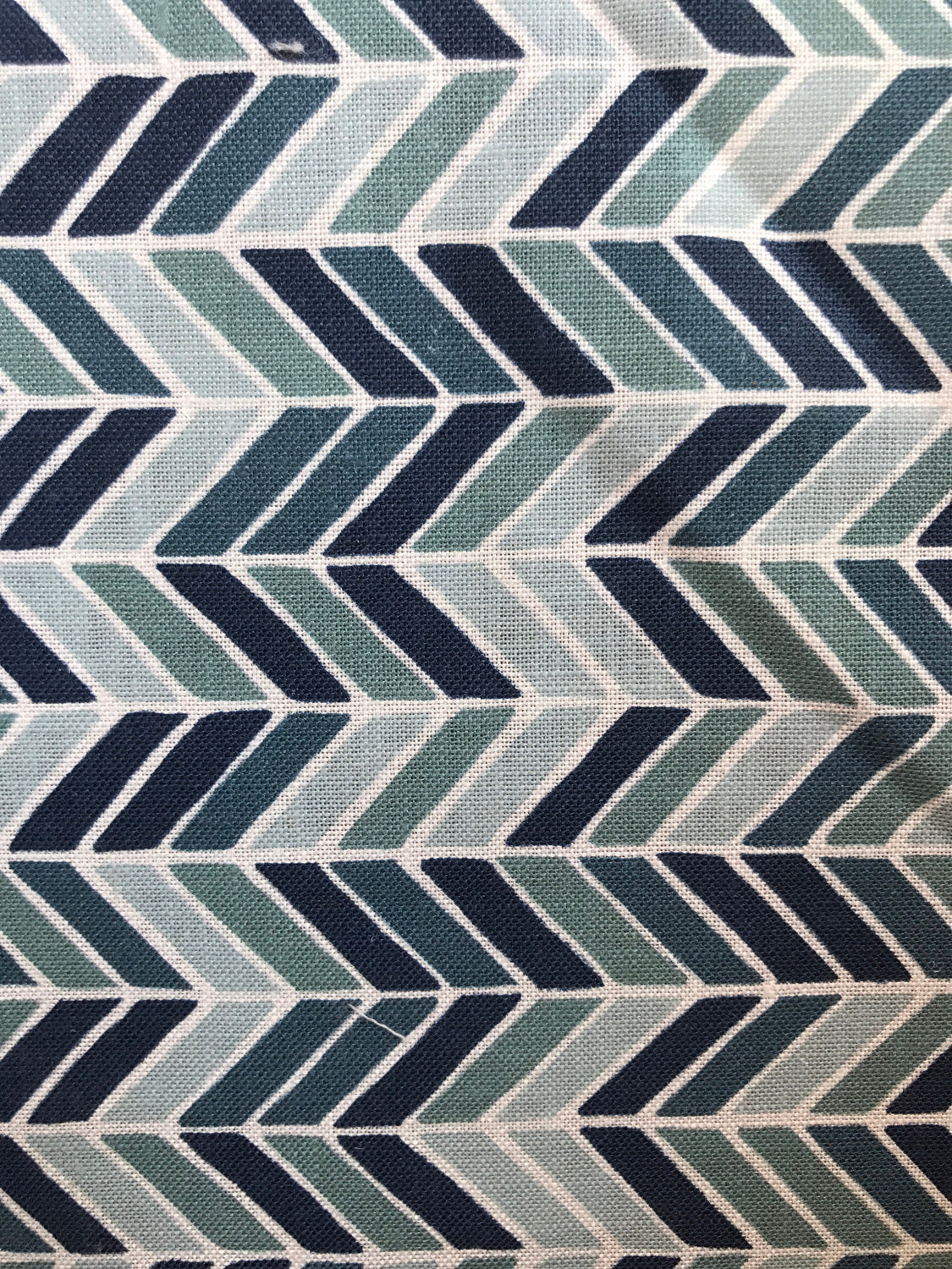 Detail of fabric in a geometric herringbone print in blue, turquoise and navy on a white field.