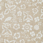 Detail of fabric in a floral print in shades of white on a tan field.