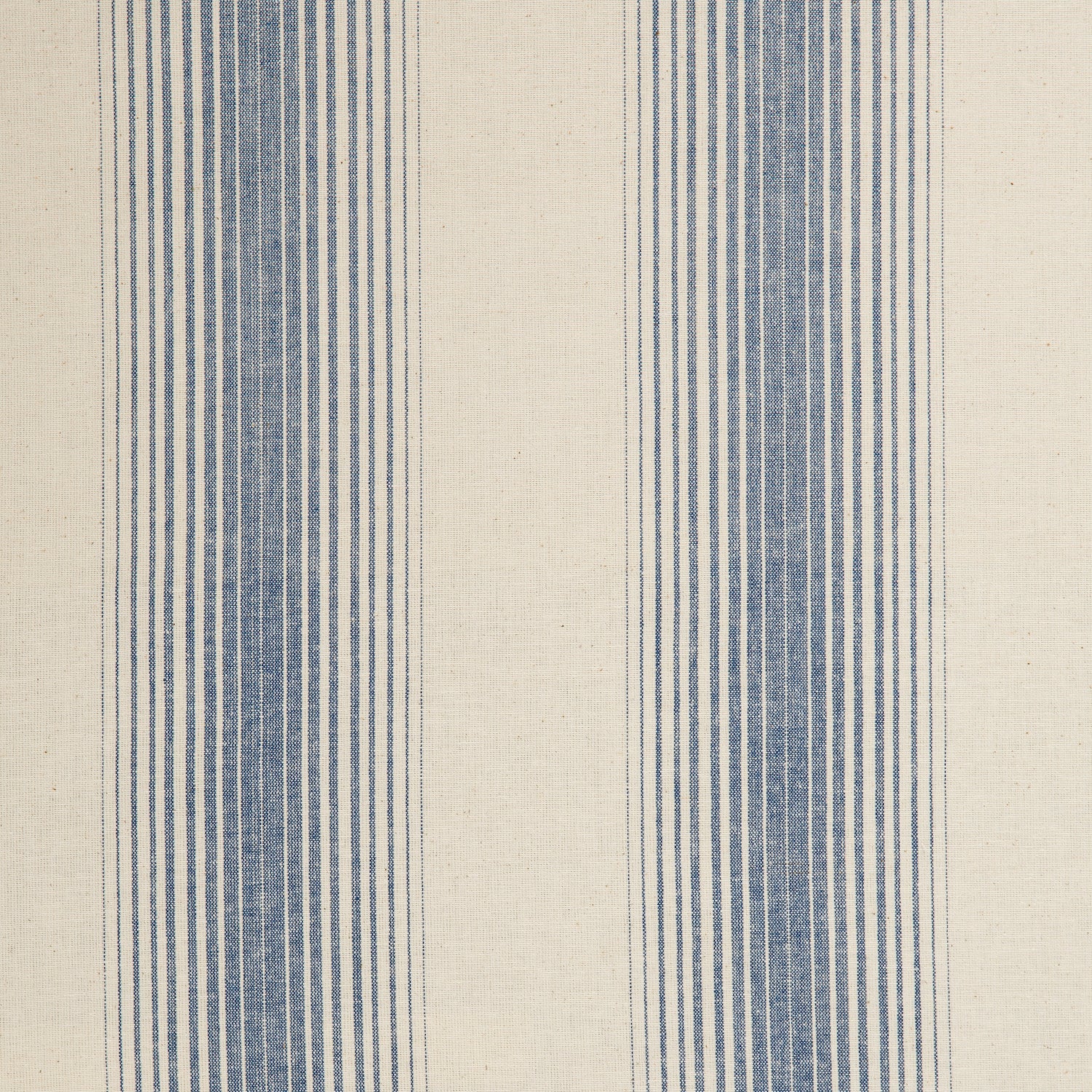 Detail of a cotton fabric in an irregular stripe pattern in blue on a cream field.