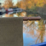 Close-up of a textured fabric with a wooden handle against a blurred natural background
