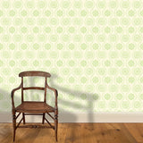 A wooden chair stands in front of a wall papered in a playful floral stripe in green on a cream field.