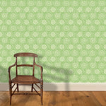 A wooden chair stands in front of a wall papered in a playful floral stripe in cream on a green field.