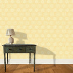 A wooden end table and lamp stand in front of a wall papered in a playful floral stripe in cream on a yellow field.