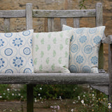 A wooden outdoor bench topped with a row of throw pillows, all in different floral prints in shades of blue, green and white.