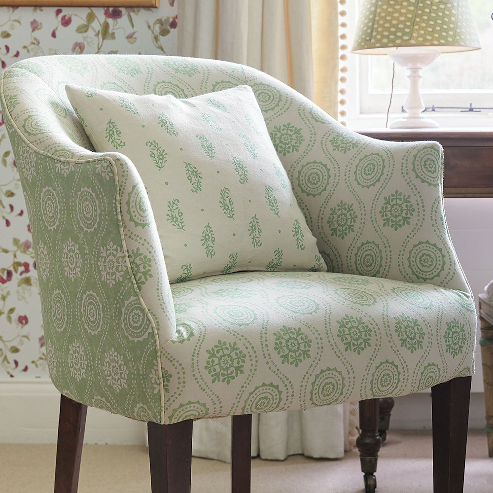 An upholstered arm chair in a playful floral stripe print in green and cream.