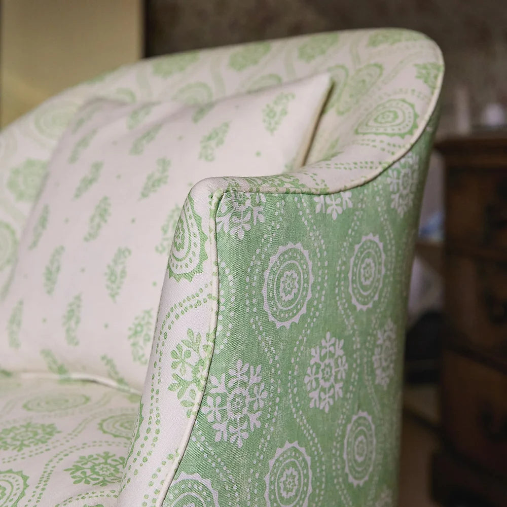 An upholstered arm chair in a playful floral stripe print in green and cream.