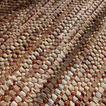 Detail of a woven leather rug in a striped grid texture in shades of brown.