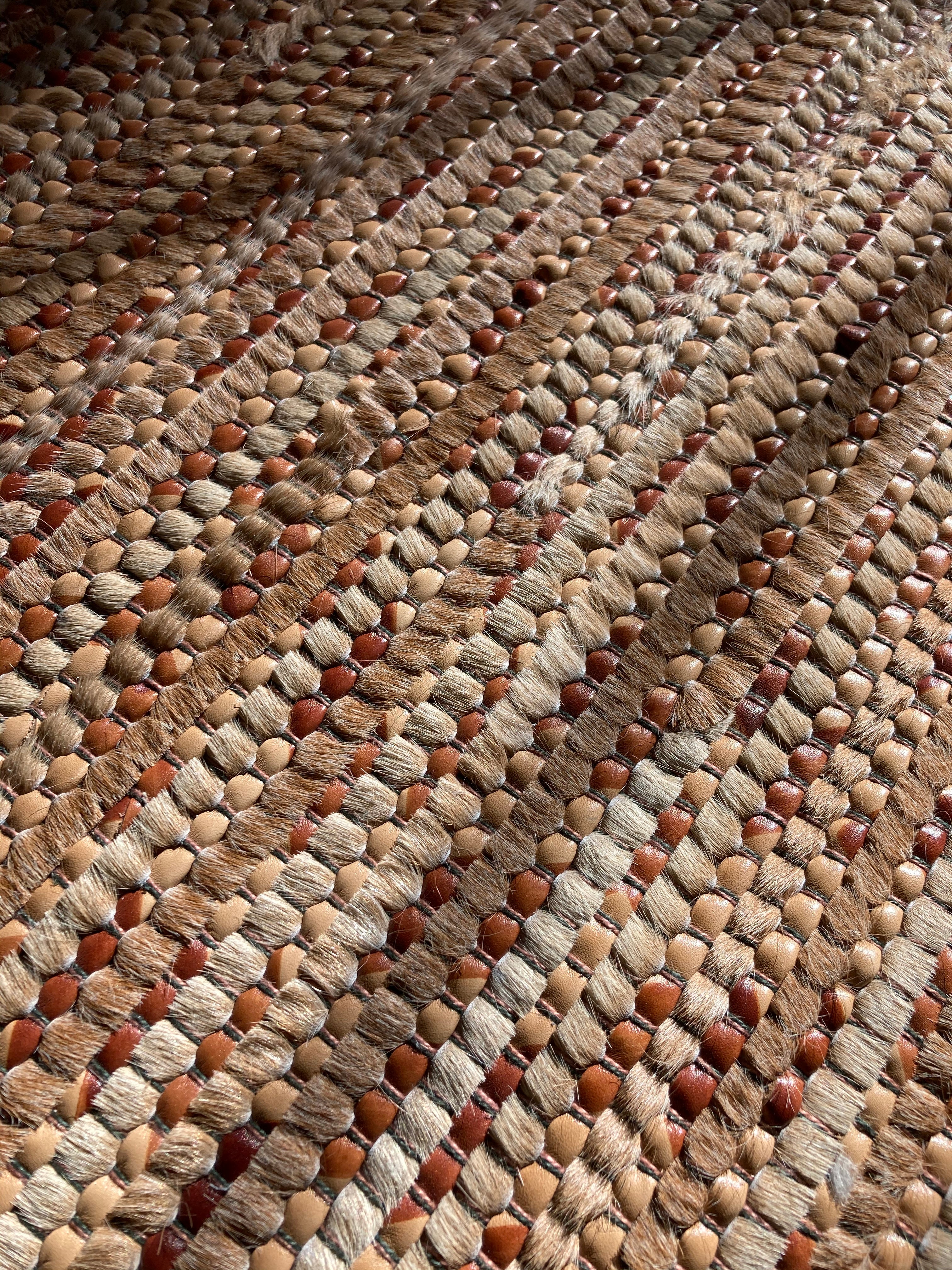 Detail of a woven leather rug in a striped grid texture in shades of brown.