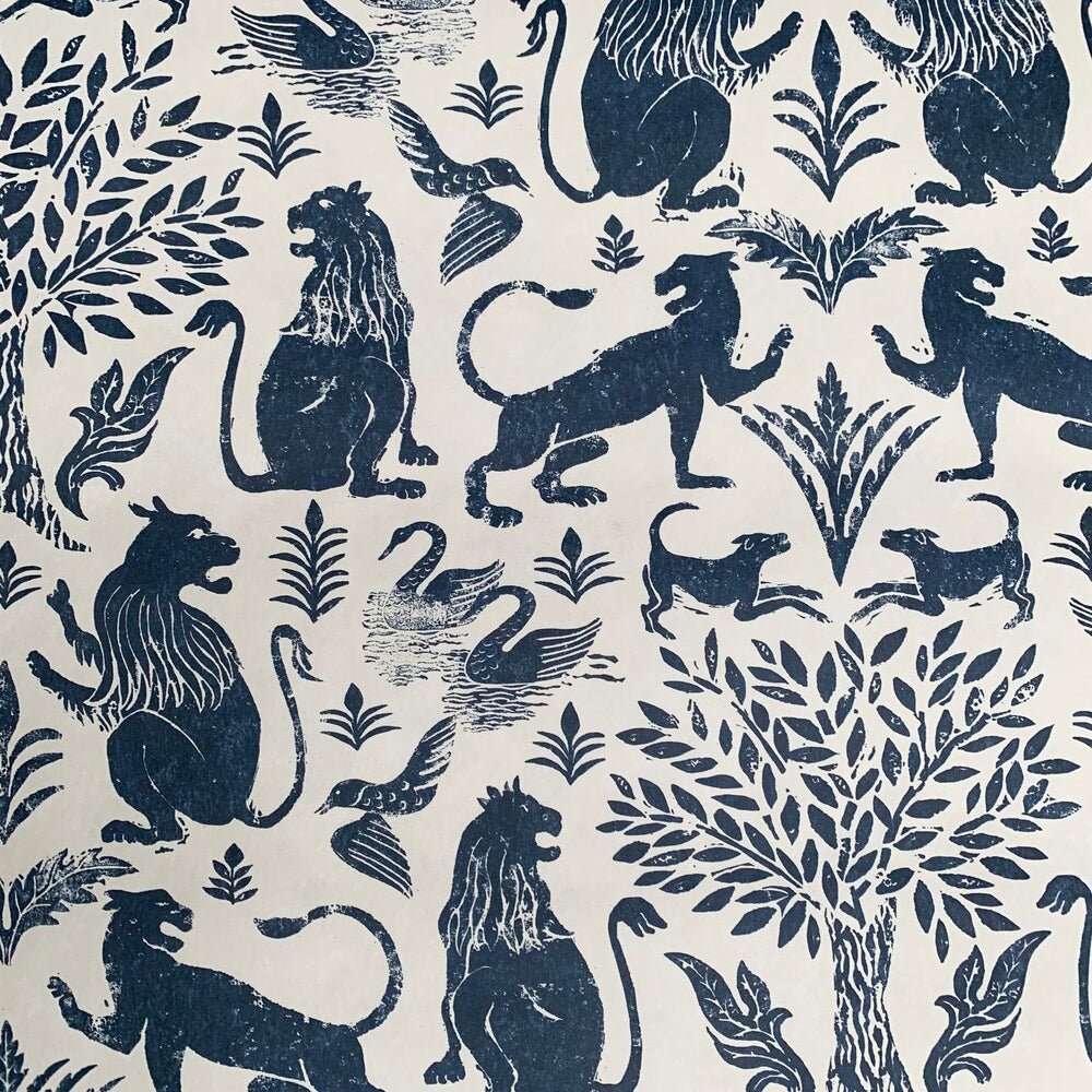 Detail of wallpaper in a lion and plant print in navy on a mottled cream field.