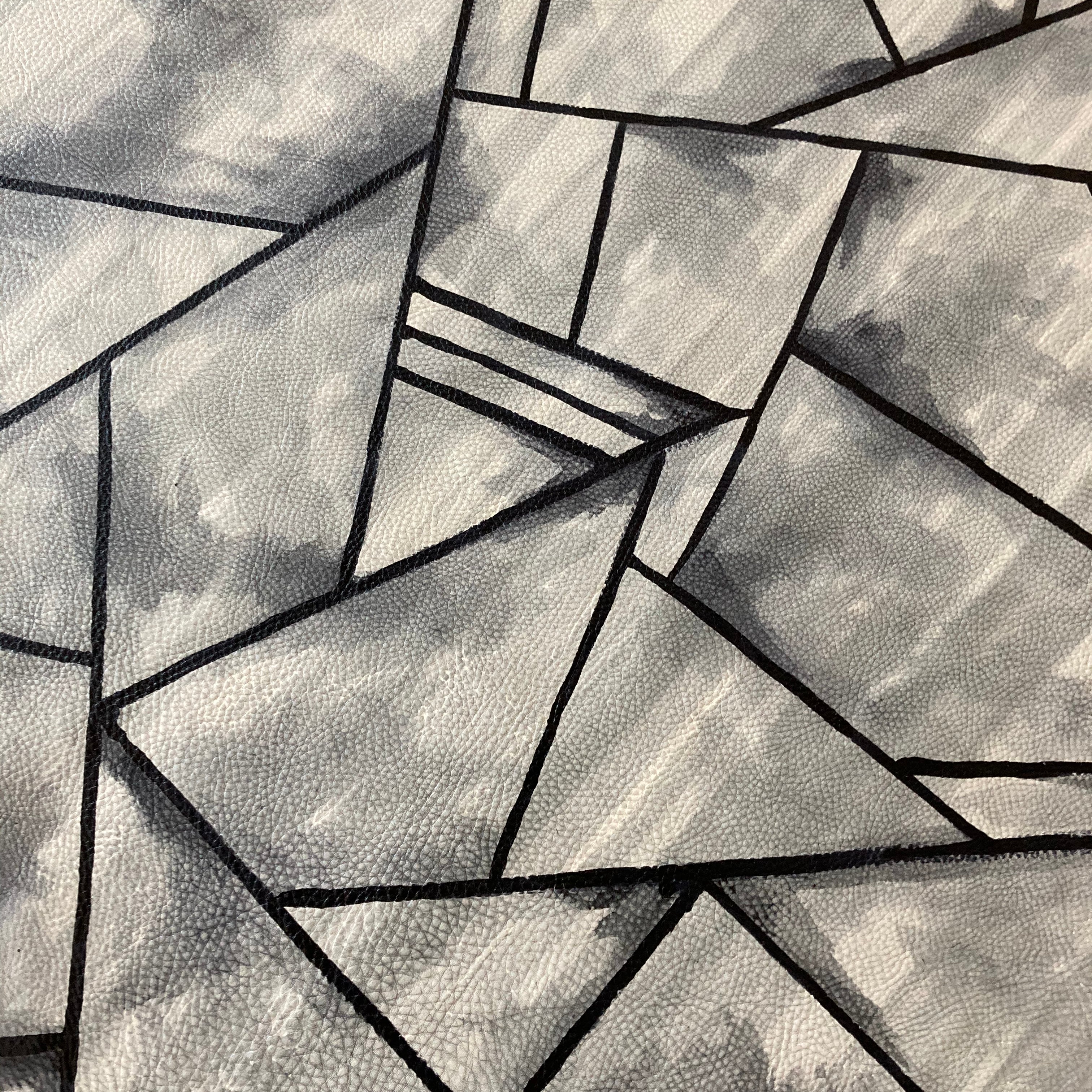 Close-up of a cowhide rug in mottled gray with a geometric black overlay.