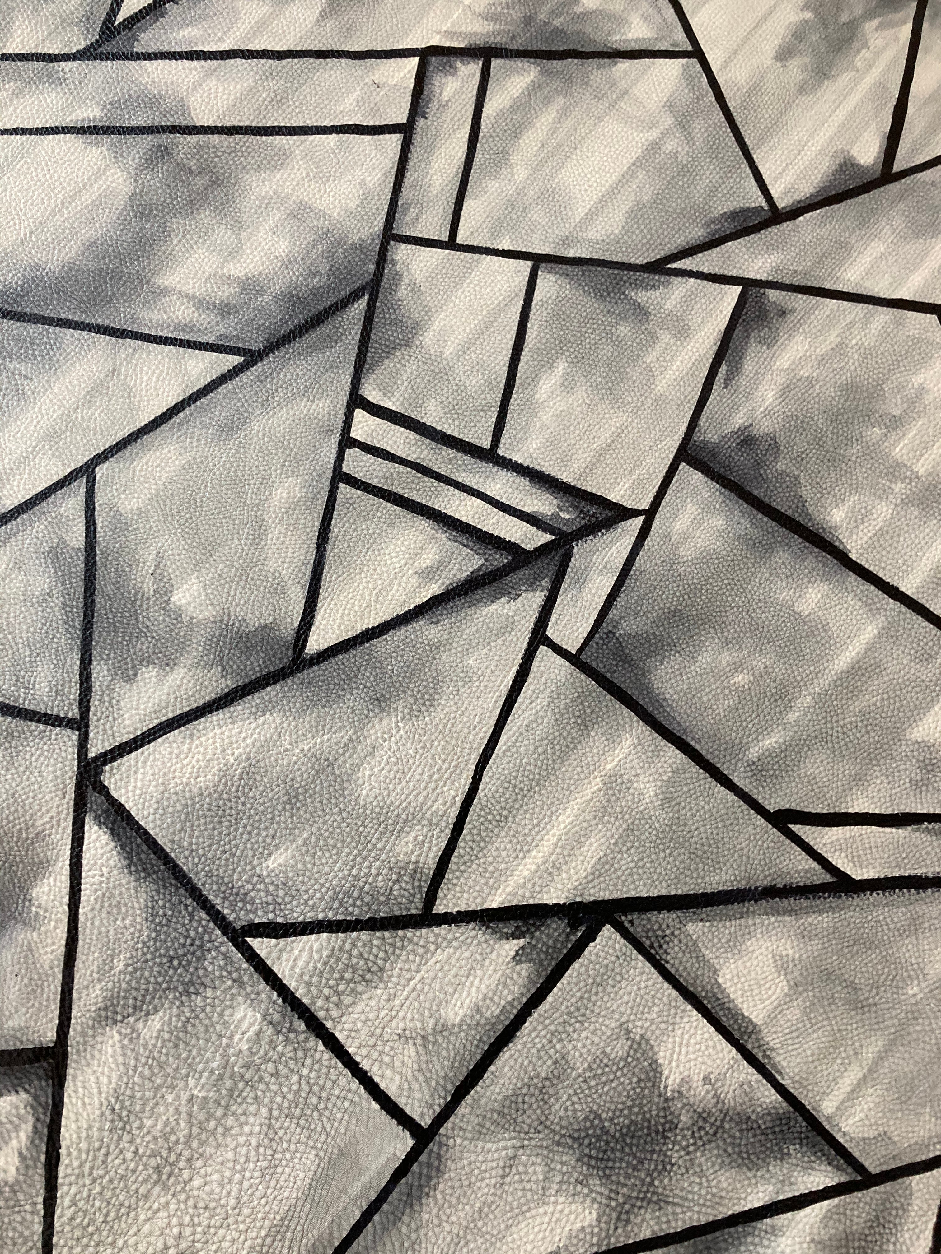 Close-up of a cowhide rug in mottled gray with a geometric black overlay.