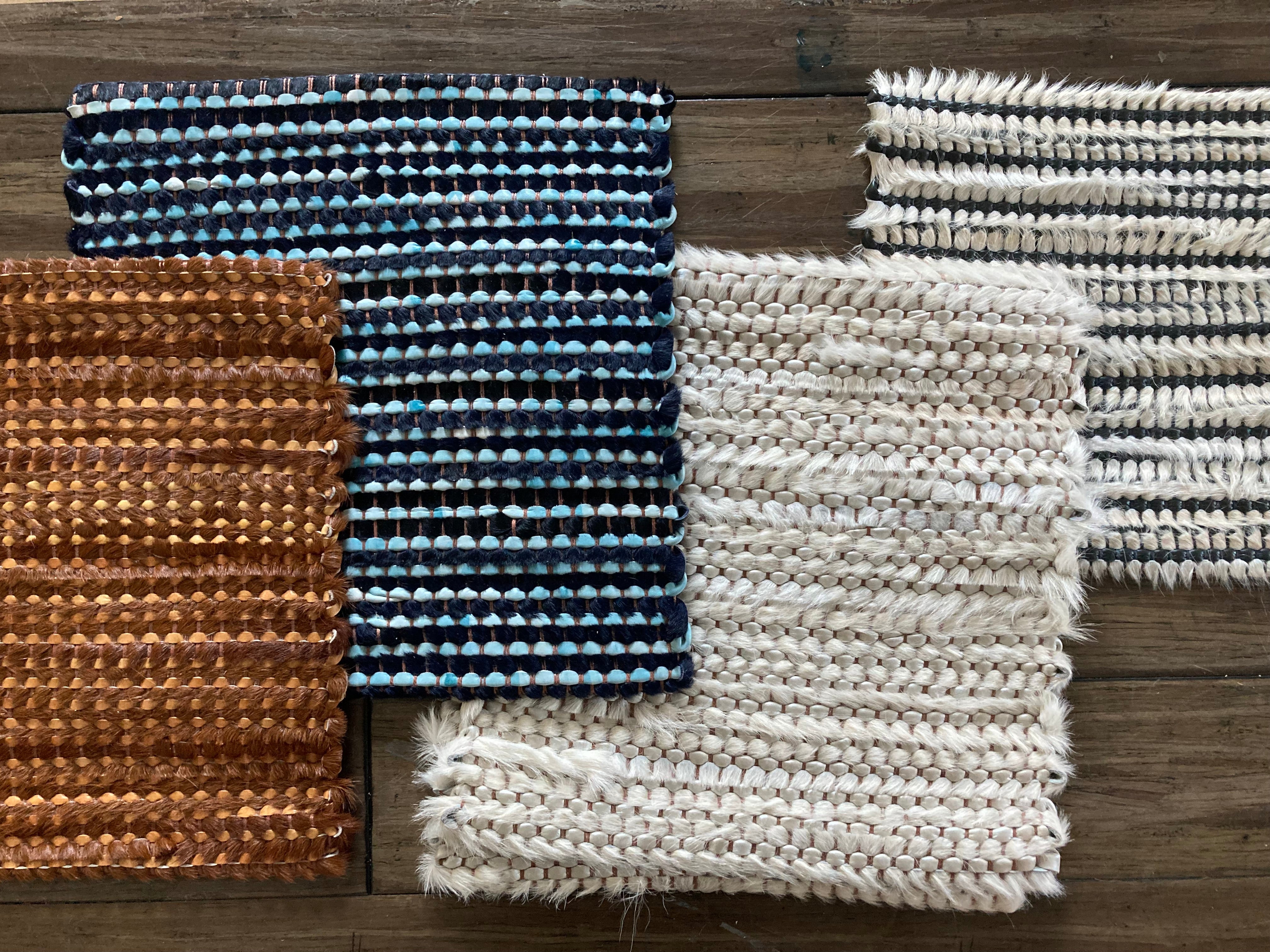 A row of woven leather rug swatches, all with striped grid textures, all in different colorways.