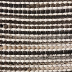 Detail of a woven leather rug in a striped grid texture in shades of brown and cream.