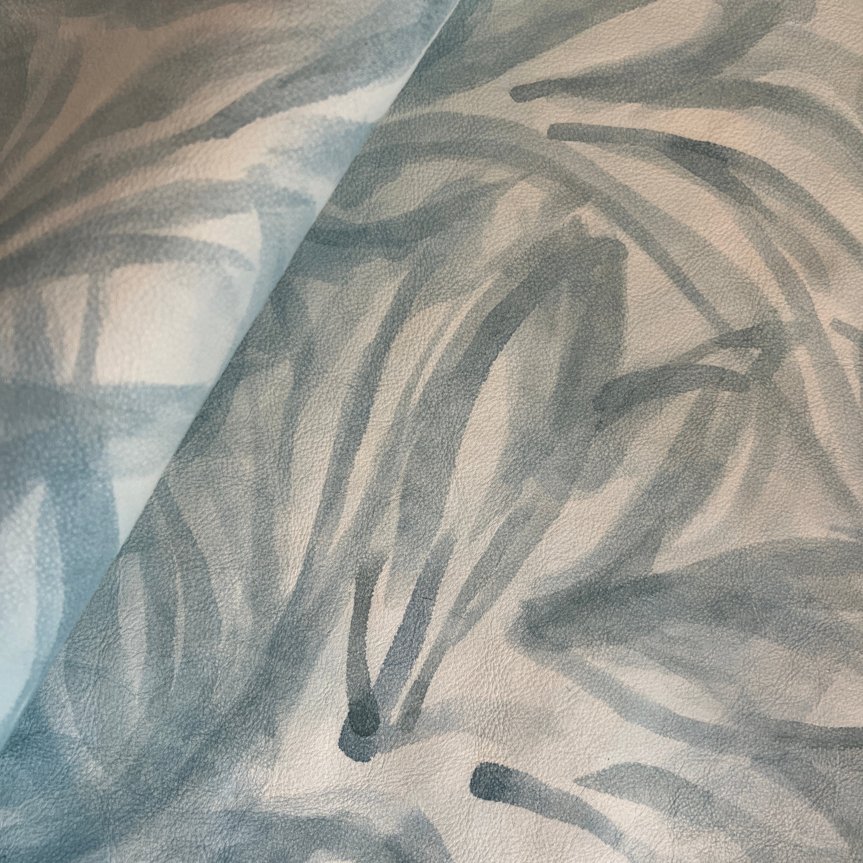 Draped upholstery leather in cream with a painterly botanical overlay in blue and gray.