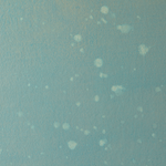 Detail of a wallpaper in a blurred paint splatter pattern in light blue on a turquoise field.