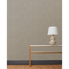End table and white lamp in front of a wall papered in a repeating curvolinear print in white on a painted gray field.