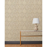 End table and white lamp in front of a wall papered in a repeating curvolinear print in rust on a painted cream field.