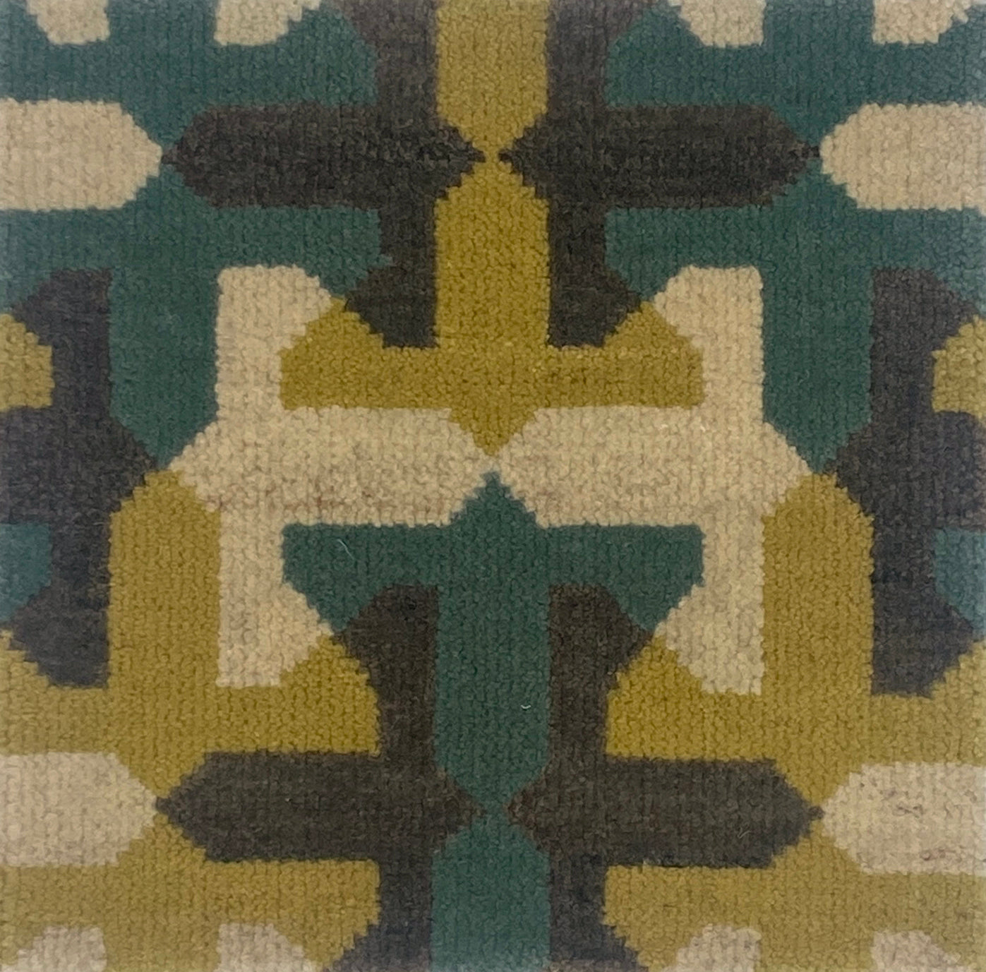 Close-up of a geometric patterned rug with green, brown, and beige colors.