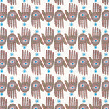 Detail of wallpaper in a playful hamsa hand print in brown, pink and blue on a white field.