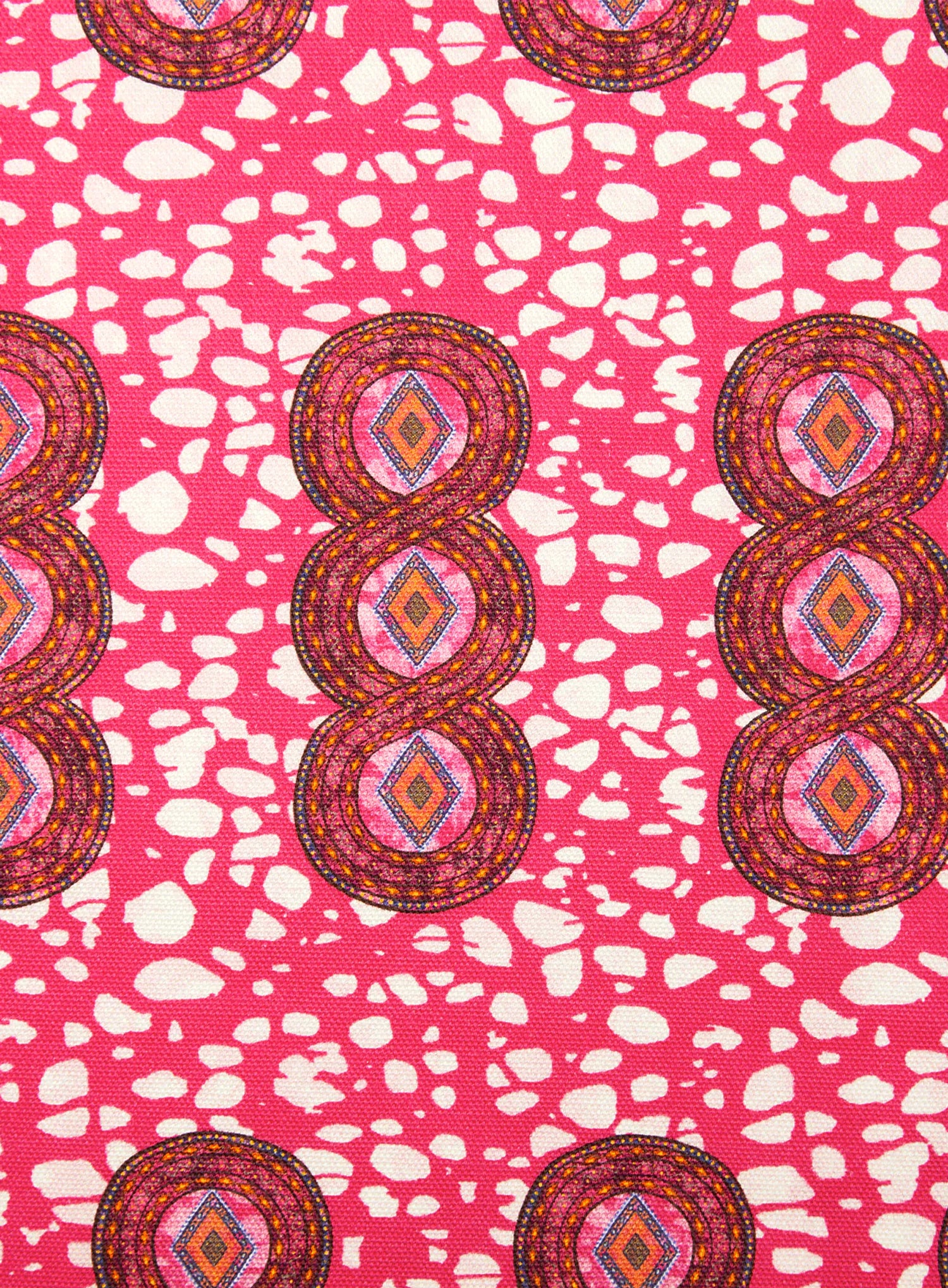 Detail of fabric in an intricate curvilinear print in shades of red, orange and pink.