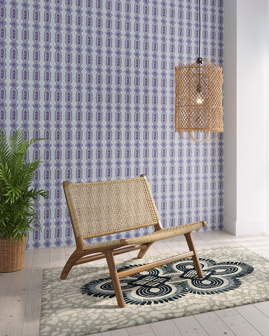 Styled living room tableau with a wall papered in a geometric stripe pattern in shades of blue, purple and navy.