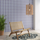 Styled living room tableau with a wall papered in a geometric stripe pattern in shades of blue, purple and navy.