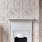 A white fireplace stands against a wall papered in a painterly bluebell pattern in white and light pink.