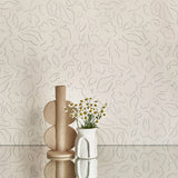 Two vases stand in front of a wall papered in a minimalist floral print in black on a cream field.
