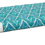 Partially unrolled fabric in an intricate diamond grid pattern in shades of blue and turquoise.