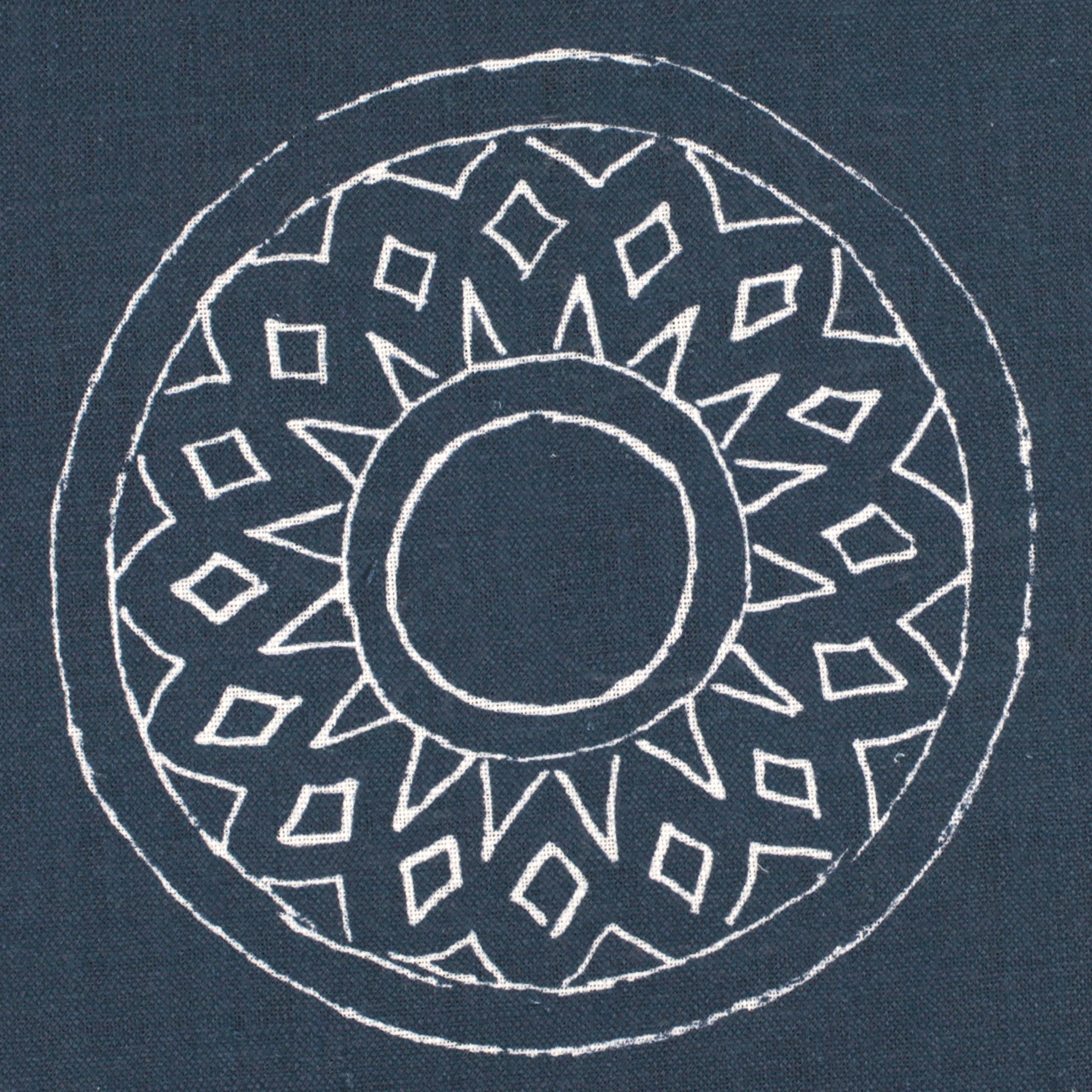 Detail of fabric in a repeating circular geometric print in white on a navy field.