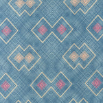 Detail of fabric in a detailed diamond lattice print in shades of red and orange on a blue field.