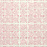 Detail of fabric in a damask lattice print in pink on a cream field.