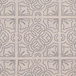 Detail of fabric in a damask lattice print in light gray on a tan field.