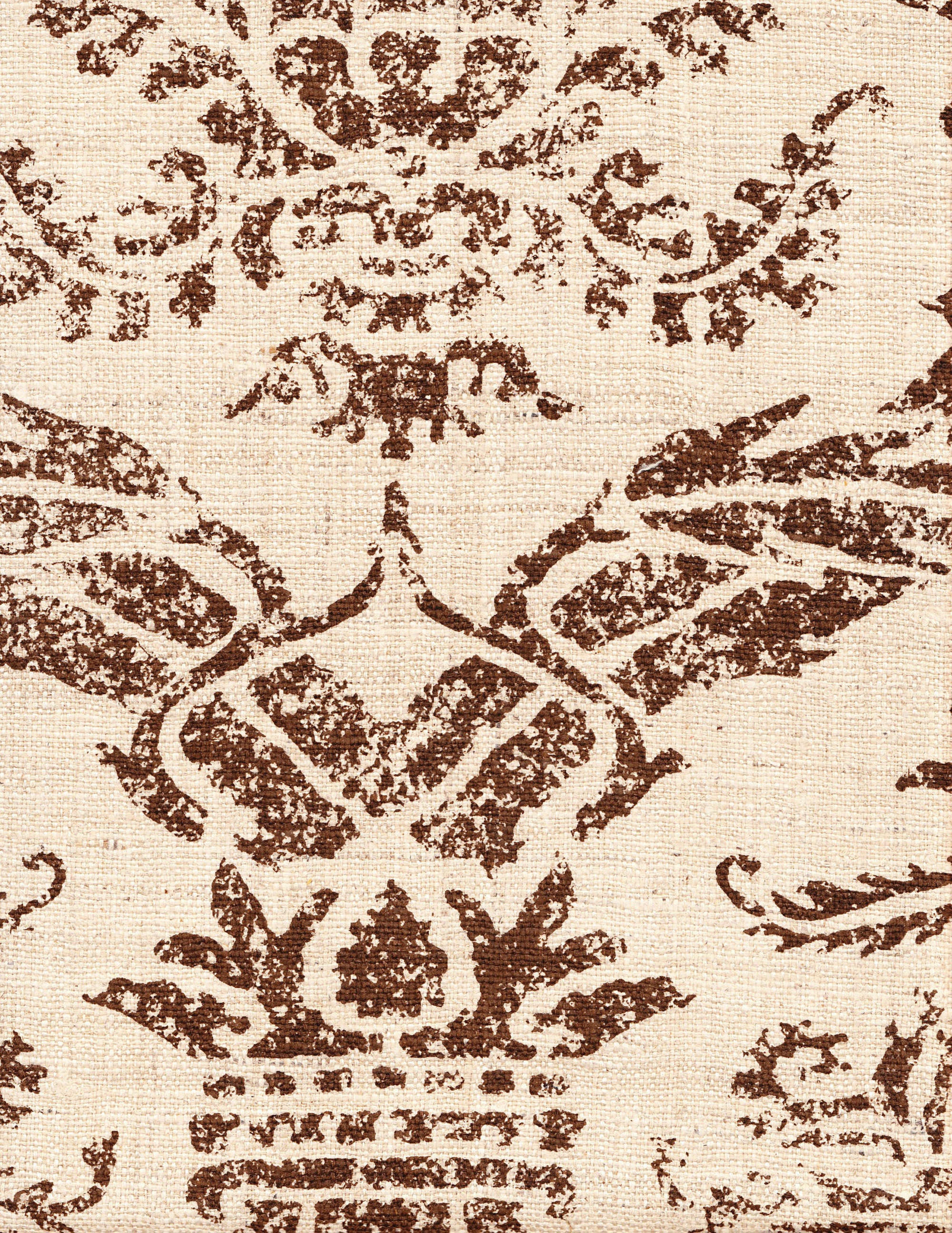 Detail of fabric in a mottled damask print in brown on a cream field.