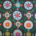 Detail of fabric in a playful floral pattern in a rainbow of colors on a gray field.