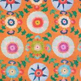 Detail of fabric in a playful floral pattern in a rainbow of colors on an orange field.