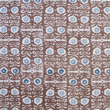 Fabric in a repeating damask print in white and blue on a brown field.