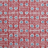 Fabric in a repeating damask print in white and blue on a red field.