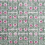 Fabric in a repeating damask print in white and pink on a green field.