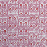 Fabric in a repeating damask print in white and red on a pink field.