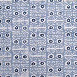 Fabric in a repeating damask print in white and navy on a blue field.