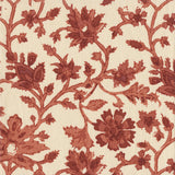 Detail of fabric in a floral damask print in shades of red and rust on a cream field.