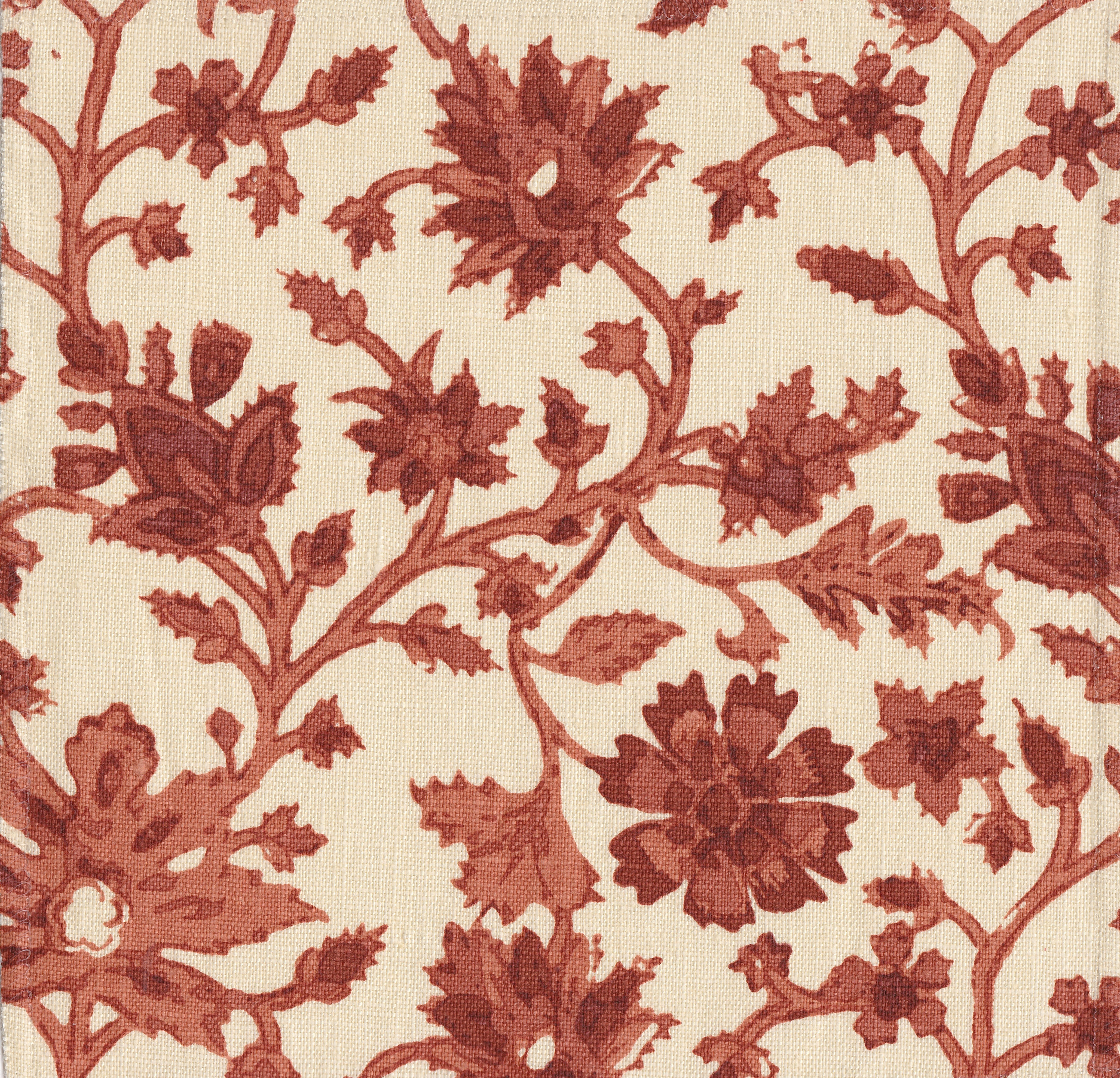 Detail of fabric in a floral damask print in shades of red and rust on a cream field.