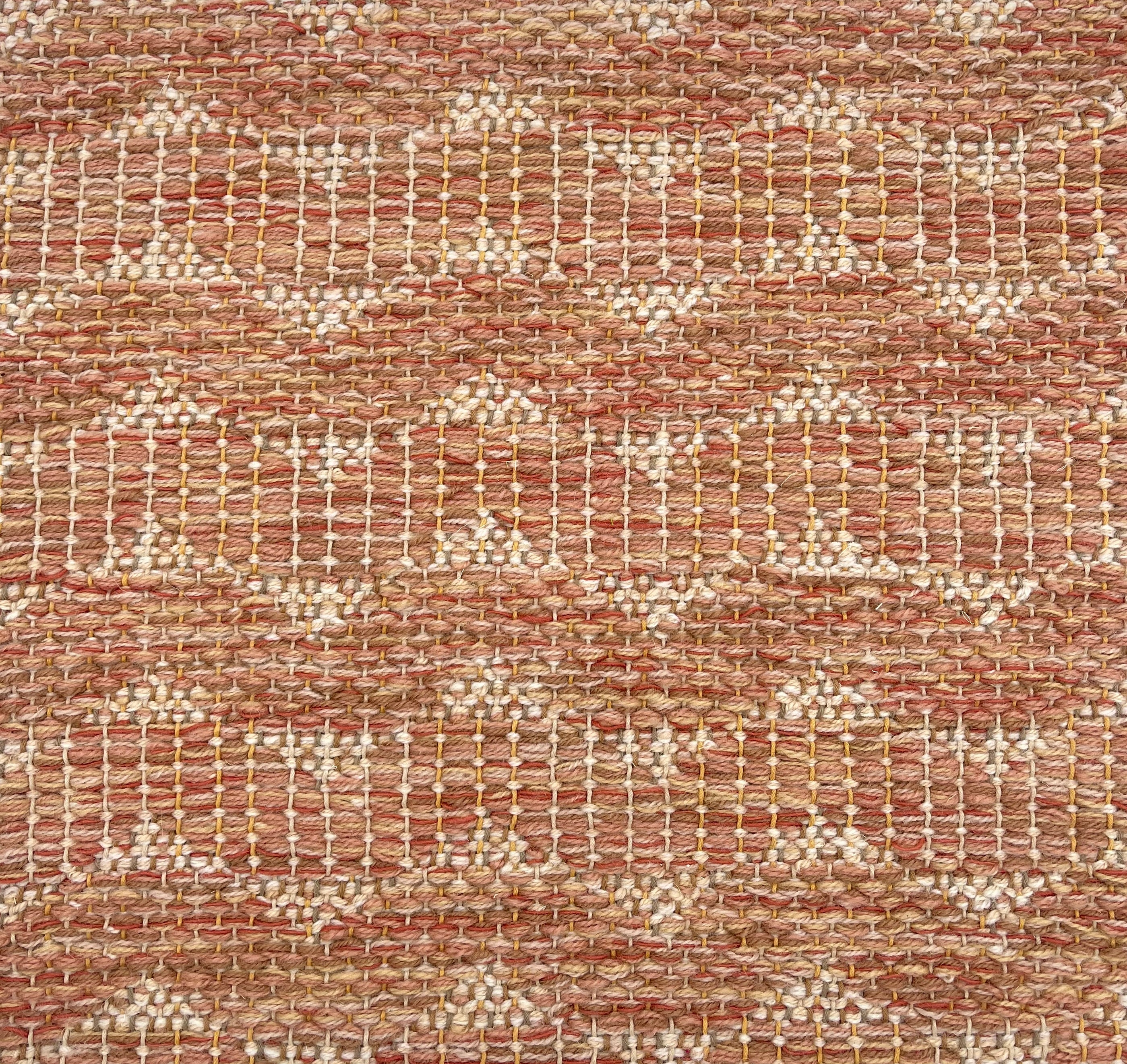 Handwoven rug detail in a contemporary design in orange red and beige