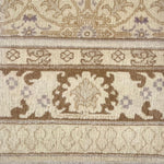 Detail of a rug with geometric and floral pattern in taupe, medium brown and lavender.