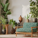 A plant-filled living space with an armchair upholstered in an abstract geometric pattern in shades of green.