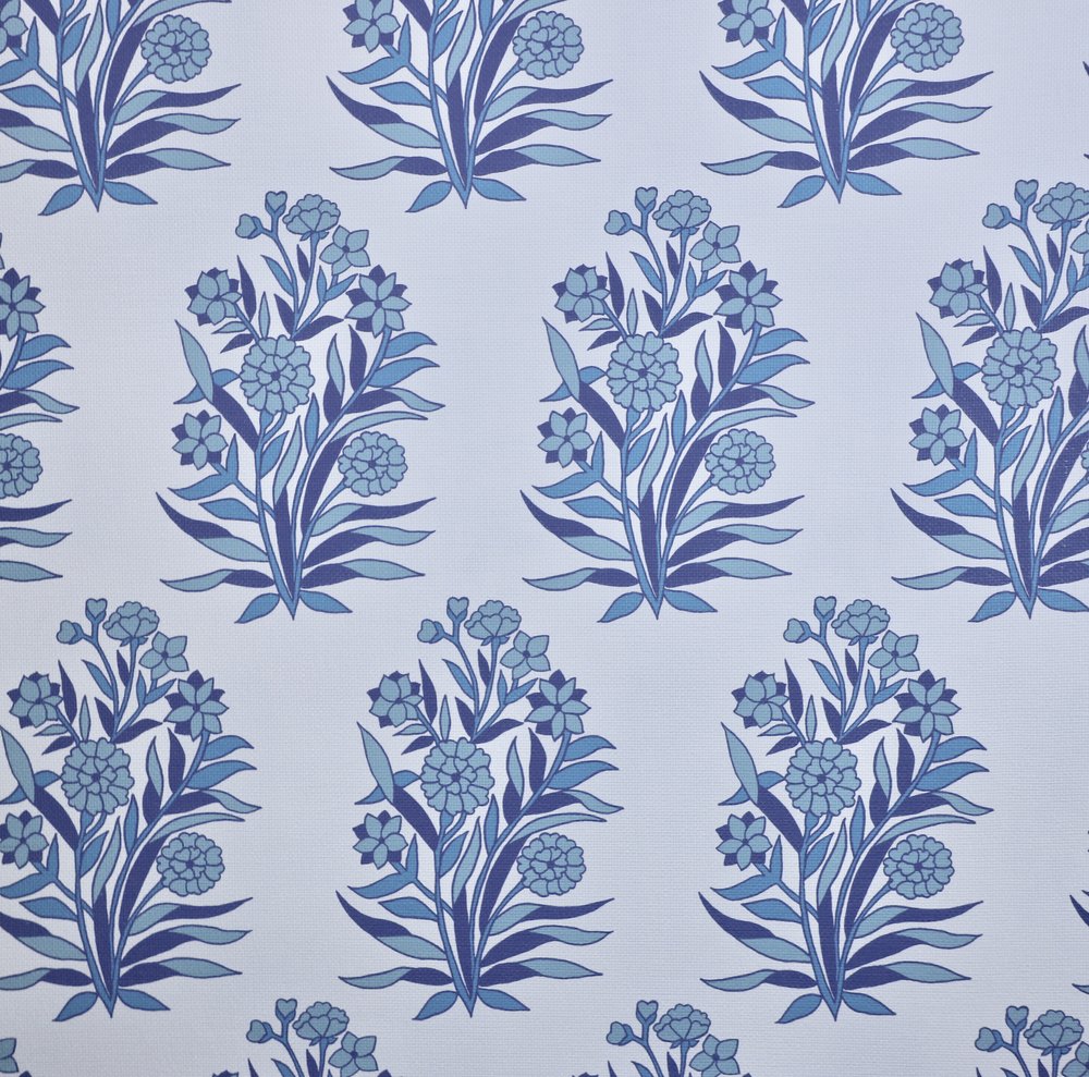 Detail of fabric in a repeating floral print in shades of blue and navy on a light blue field.